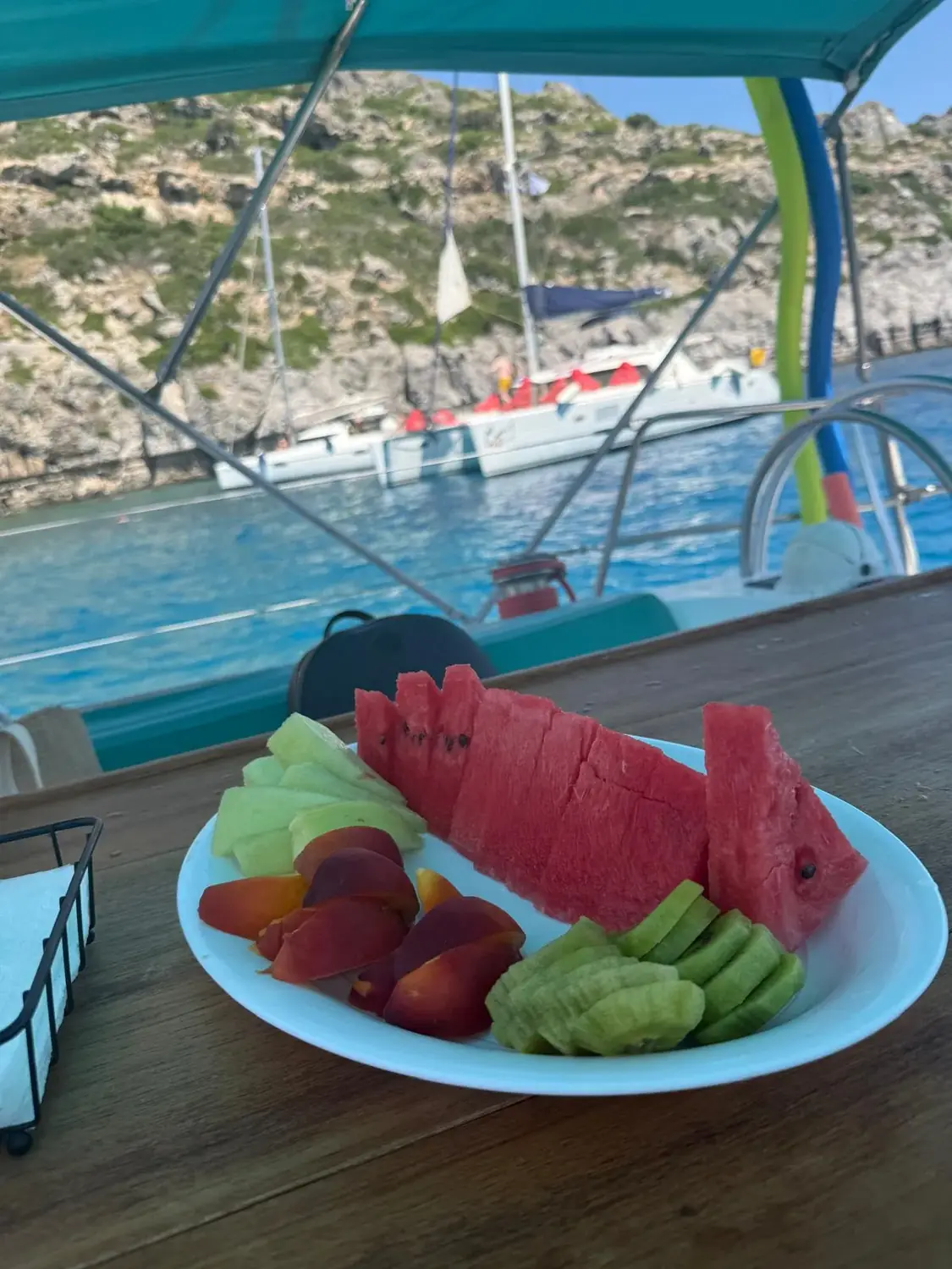 A platter of watermelon, melon, peach and kiwi served on deck